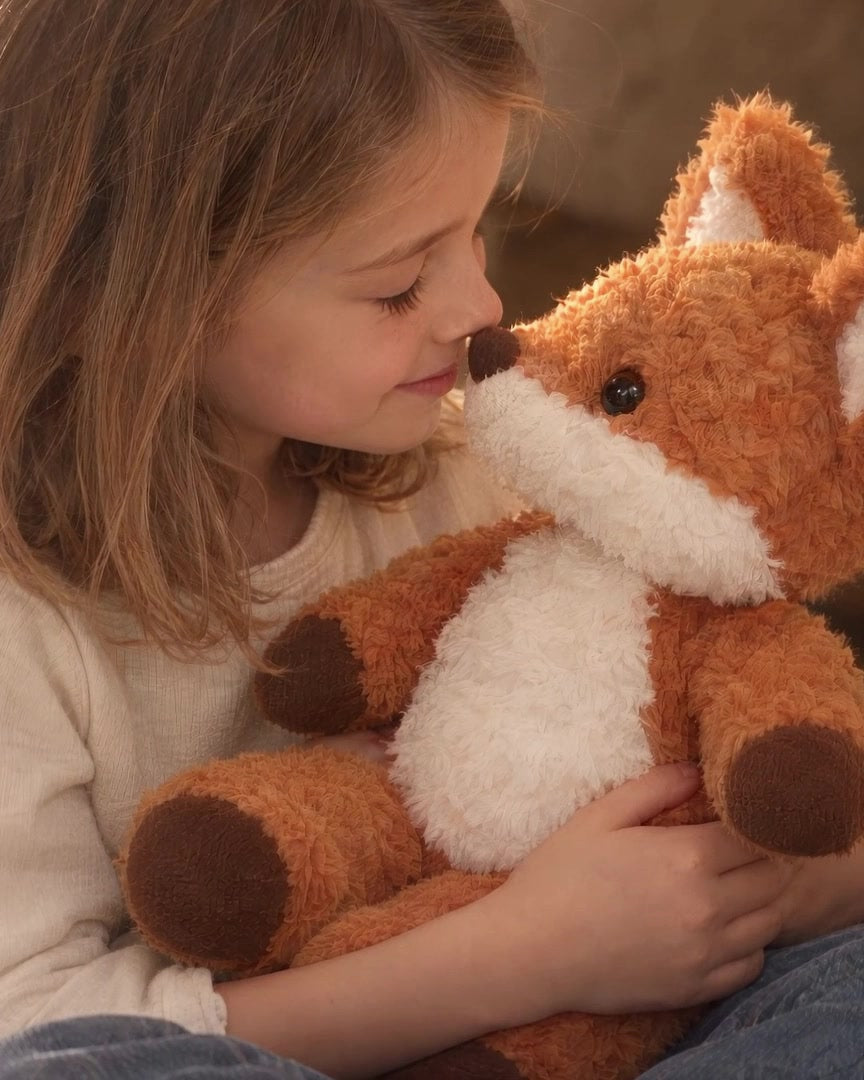 A child cuddles Rovan the fox plush in a softly lit linen play fort.