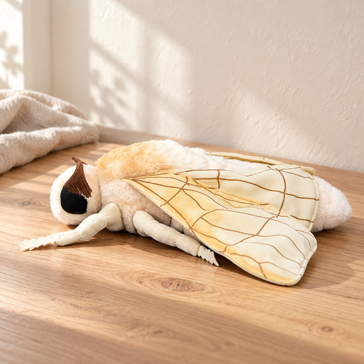 Vesper Golden Ivory - 27 cm moth and insect plush on a pale oak table