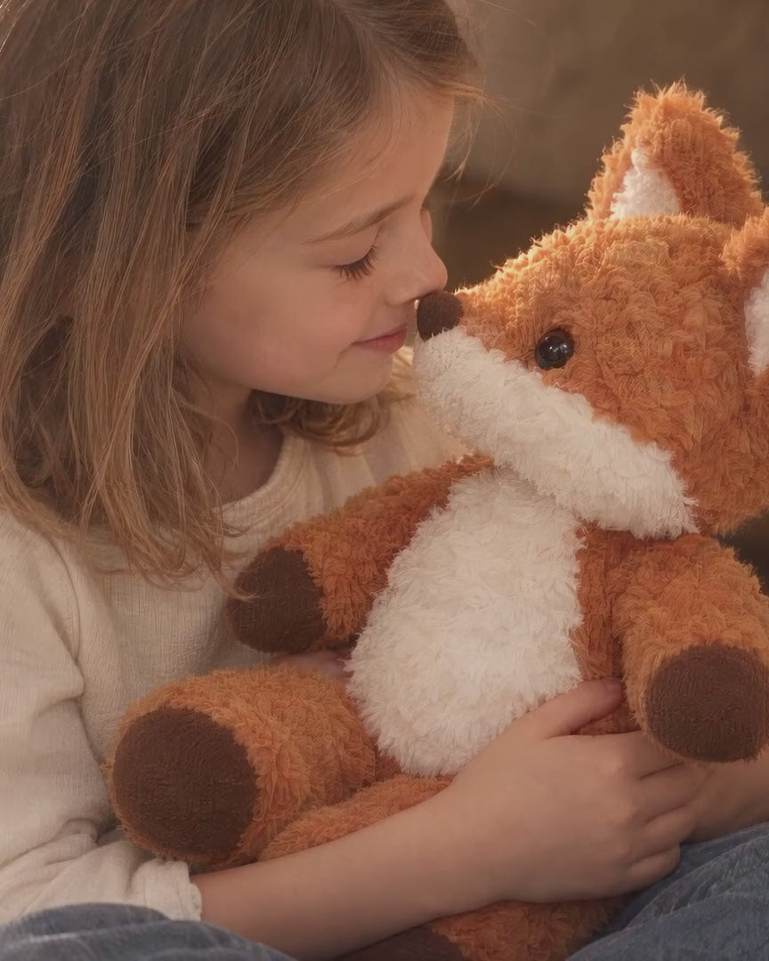 Rovan the fox plush shared with a child in a softly lit linen play fort.